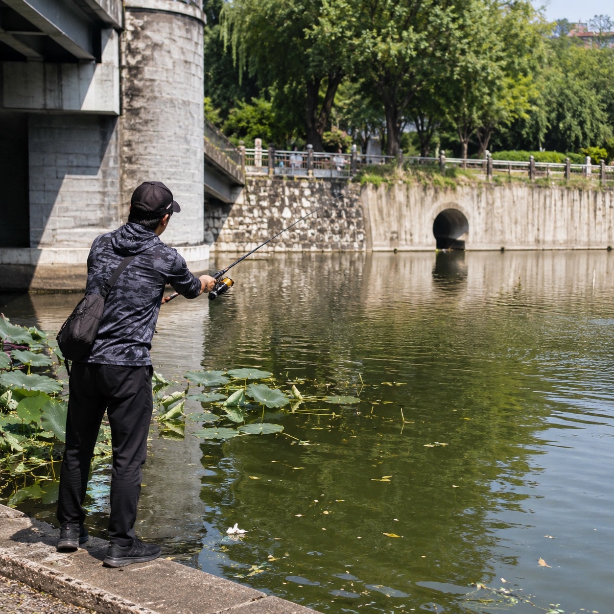 Lure angler casting beside an urban bridge and canal